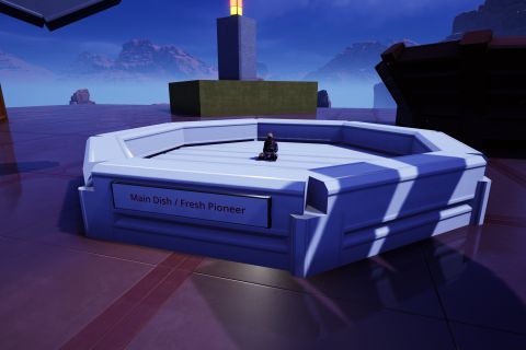 Image from the game Satisfactory featuring a scene depicting two invisible ghosts wearing bibs eating a meal at a dinner table. The scale of the scene is such that the game's Pioneer is about the size of the tines on the fork one of the ghosts is using. The shot focuses on the plate one of the ghosts is eating from, (both invisible ghosts are not in shot) with one of the game's Pioneers sitting in the center of a white plate. A sign on the front of the plate reads "Main Dish / Fresh Pioneer". In the rear of frame is a relatively large glowing candle.